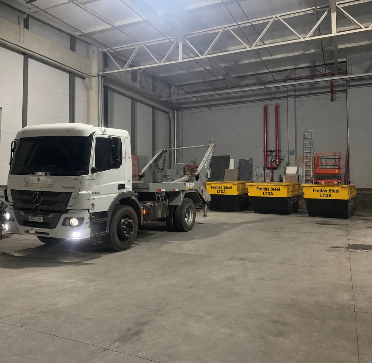 Galpão da Freitas Steel com caminhão e caçambas amarelas alinhadas